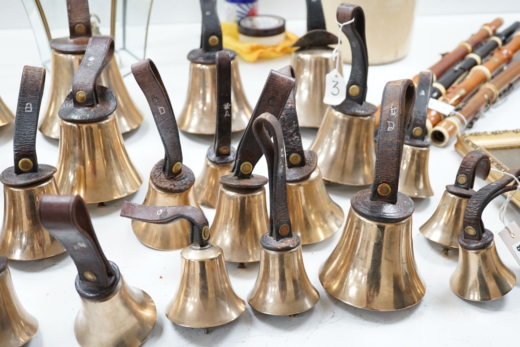 A rare set of 32 Whitechapel musical handbells, full chromatic scale, circa 1900, largest 23cm, including leather strap.